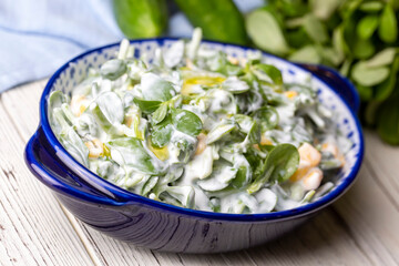 Purslane salad with yogurt in bowl on wooden background.