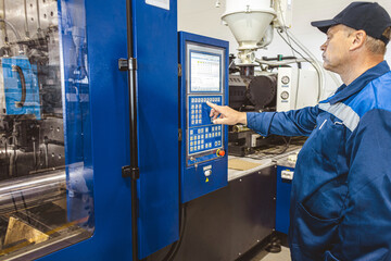 A worker presses a button and starts an automatic manufacturing process in a factory