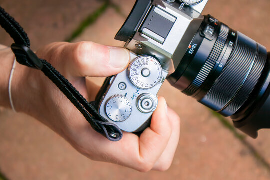 Closeup of a mirrorless camera body with lens held by a person hand with strap