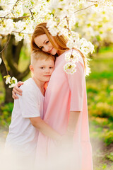 mother and son teenager in a flowering spring cherry orchard.