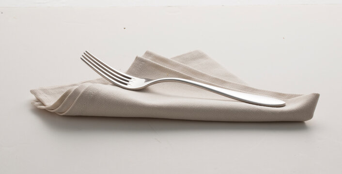 Tenedor sobre servilleta en fondo blanco, cuberter&iacute;a. Fork on napkin on white background, cutlery.