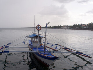 Fishing boat anchored on the sea on a cloudy sunny day.