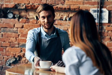 happy bartender serving a cup of coffee to a patient in a cafe drink brick wall interior