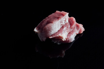 A closeup shot of raw pork tenderloin on a black background