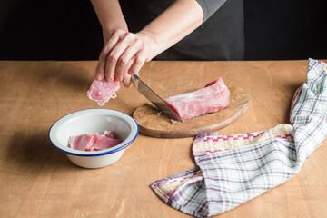 A person slicing pork tenderloin for making a meal