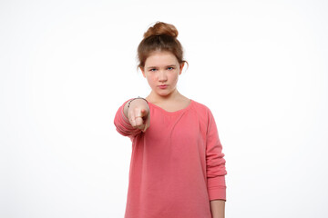 Displeased young girl is pointing finger at camera and to you, angry and furious with you. Studio...