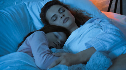 Woman hugging child while sleeping during night