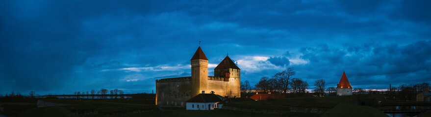 Fototapeta na wymiar Kuressaare, Saaremaa Island, Estonia. Episcopal Castle In Evening Blue Hour Night. Traditional Medieval Architecture, Famous Attraction Landmark. Old Tower. Panorama, panoramic view Copy space