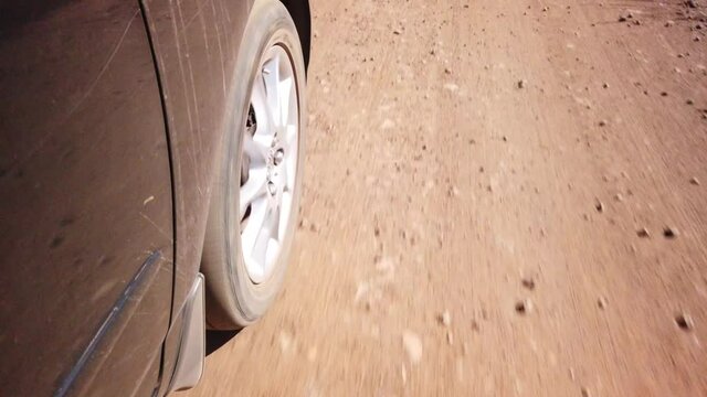 Close up of a car wheel driving on a sand gravel road
