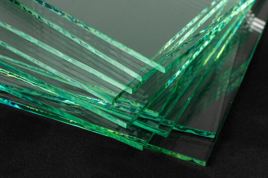 Sheets of Factory manufacturing tempered clear float glass panels cut to size. Dark background