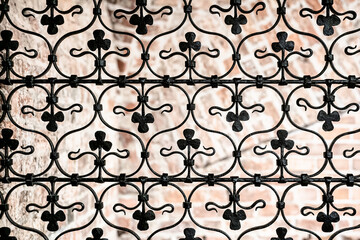 Black wrought iron metal grille with decorative details. Macro photo.