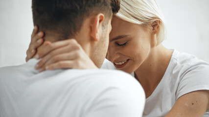happy blonde woman hugging boyfriend on blurred foreground