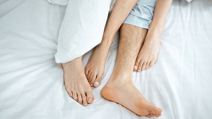 top view of barefoot couple lying on bed