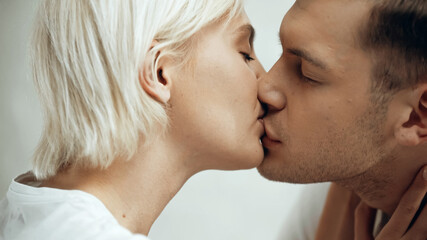 close up of couple with closed eyes kissing at home