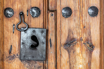 Antique wooden door with nails and an old lock. Rustic and retro old door full of knots and scratches. Vintage wood texture surface, wood vein. Pareidolia, faces in wood grain.