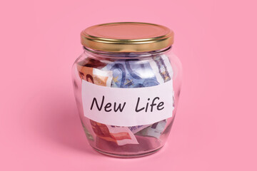 Money box with words New Life on sticky note paper. Euro banknotes in glass money jar with savings label, financial, saving. Jar full of cash, save money concept, expense control.