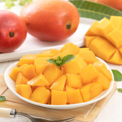 Diced fresh mango fruit on a white plate with leaves.
