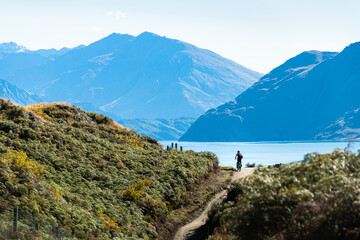 Tourist riding the bike on Glendhu Bay track along Lake Wanaka with mountains in the distance,...