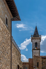 Fototapeta na wymiar Vertical view of the bell tower of the church of Santa Croce and the walls of the Conti Guidi castle in the historic center of Vinci, Florence, Italy