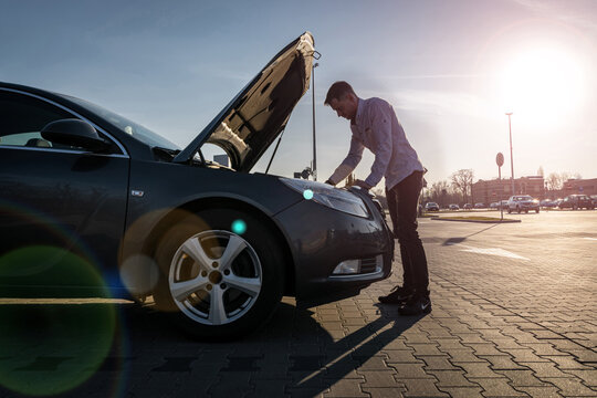 Car problem. Driver man near open hood auto after accident triangle on road. Vehicle broken down or motor car engine problem concept. - Powered by Adobe