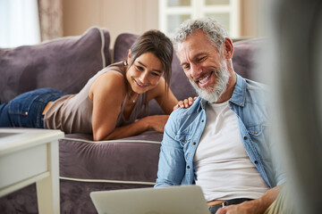 Delighted bearded man looking at screen of laptop