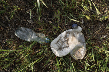 Concept of reuse - Closeup of plastic garbage. Empty plastic bottles are thrown away on the green grass.