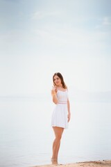 Beautiful woman in a white dress walking on the beach.Relaxed woman breathing fresh air,emotional sensual woman near the sea, enjoying summer.Travel and vacation. Freedom and inspiration concept