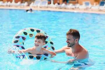 Father and son having fun in swimming pool. Family vacation
