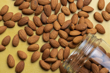Pile of peeled raw almonds on a yellow table