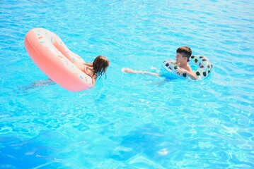 Cheerful brother and sister swimming in the pool