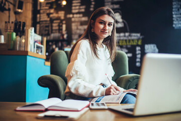 Smiling woman taking notes in textbook