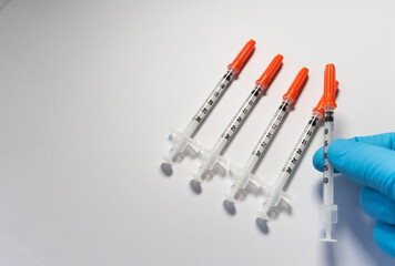 A sanitary doctor with gloves, picks up a vaccine from among all the ones that are placed. On white background with copy space.