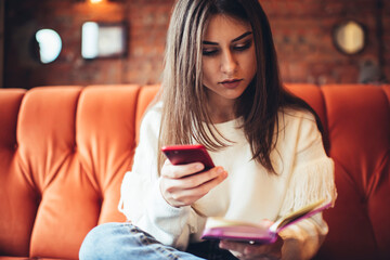 Focused woman surfing smartphone and reading notebook