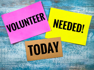 Colorful paper with text VOLUNTEER NEEDED TODAY on blue wooden background. - Powered by Adobe