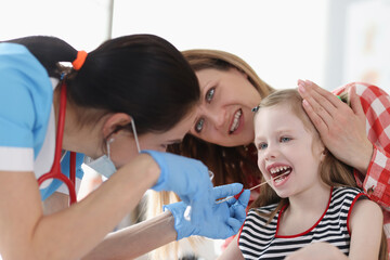 Doctor taking buccal dna swab from little girl in clinic