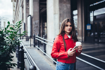 Serious woman with coffee and smartphone