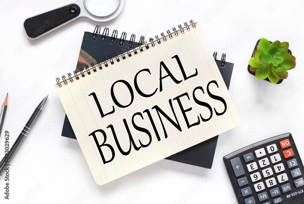 Poster local business. an open notebook lies on a closed notebook near a calculator and a magnifying glass 