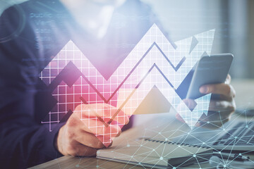 Double exposure of man's hands holding and using a digital device and arrows hologram drawing. Success concept.