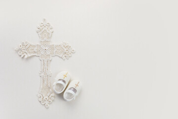 Christening background with baptism baby shoes, and cross on pastel background