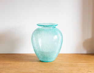 Mid-century modern turquoise blue glass vase - on a wooden table  with white background