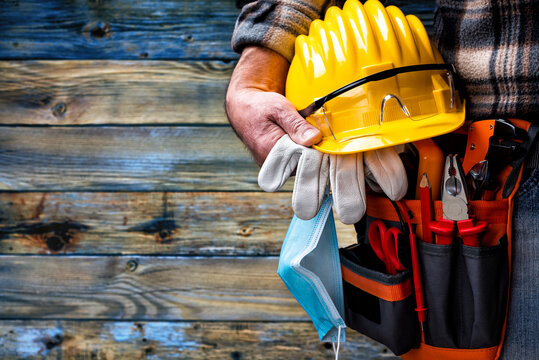 Electrician Technician With Tool Belt And Surgical Mask On Rustic Light Wood Background. Electricity. Covid-19 Prevention.