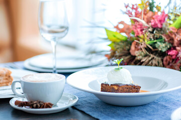 Chocolate cake with a ball of white ice cream decorated with mint leaf and caramel syrup is served on a large white plate in the restaurant. Restaurant menu.
