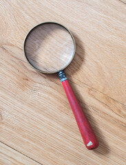 Vintage magnifying glass on wooden table / floor