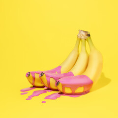 Bunch of healthy ripe yellow bananas with vibrant pink dripping paint and puddle on yellow background. Creative summer fruit food concept. Trendy pop art aesthetic.