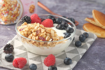 Granola and berries in bowl on pink background 