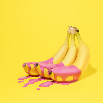 Naklejki Bunch of healthy ripe yellow bananas with vibrant pink dripping paint and puddle on yellow background. Creative summer fruit food concept. Trendy pop art aesthetic.