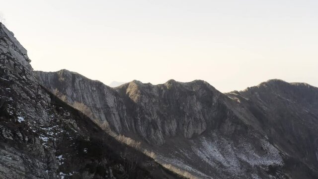 Aerial view over snow covered mountain slope during early spring. HDR. Snow and ground on a mountain range on bright sky background.