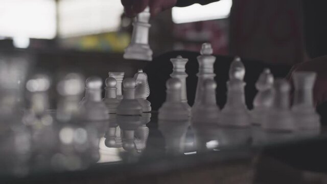 main homme joue au &eacute;checs en verre dans une piece sombre  
