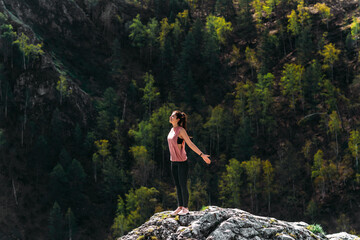 Naklejka na ściany i meble Healthy lifestyle and relaxation concept. Yoga in the fresh air. Happy woman doing yoga exercises. Meditation and relaxation. A woman practicing yoga in the mountains. A woman meditates in nature
