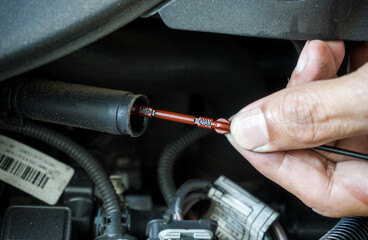 Selective focus of Dipstick on blurred fingers owner of car to checking  
Engine Oil Level with lower engine oil background.